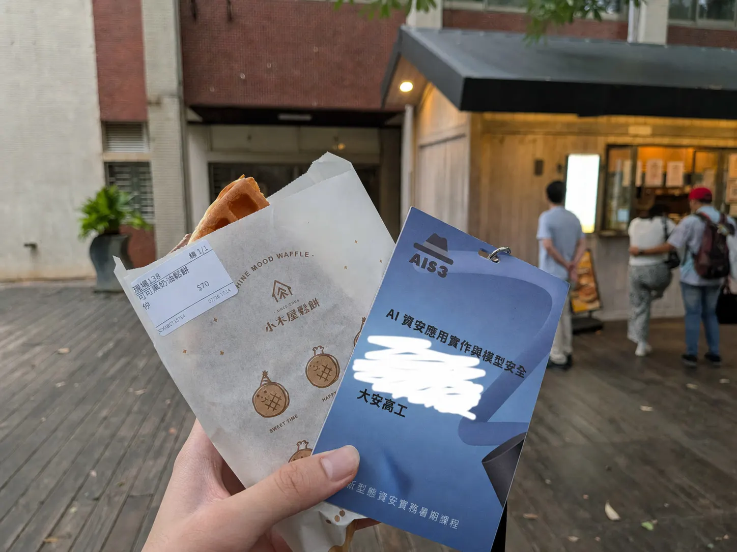 AIS3 下課後，手上拿著鬆餅和活動名牌